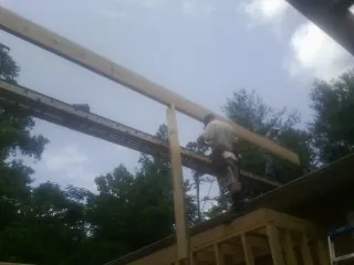 Carpenter setting a ridge beam over a new addition frame — Ice Dam Removal by Roofing Brothers in Hughson