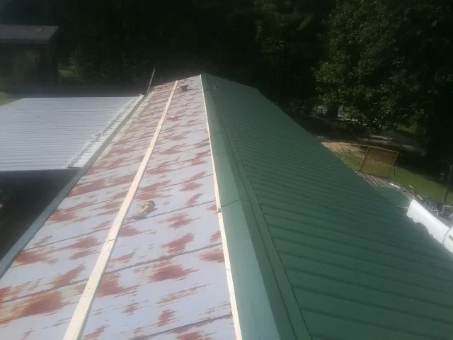 Old rusted panels beside newly installed green metal roofing — Wind Damage Roof Repair by Roofing Brothers in Hughson