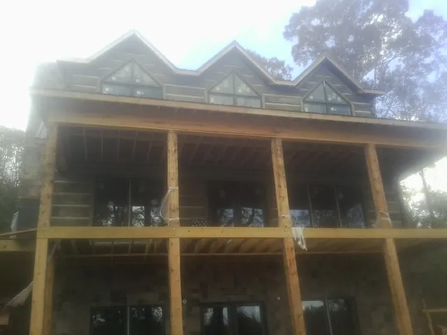 Dormers and porch framing on a large log home under construction — Roof Coating work by our crew in Hughson