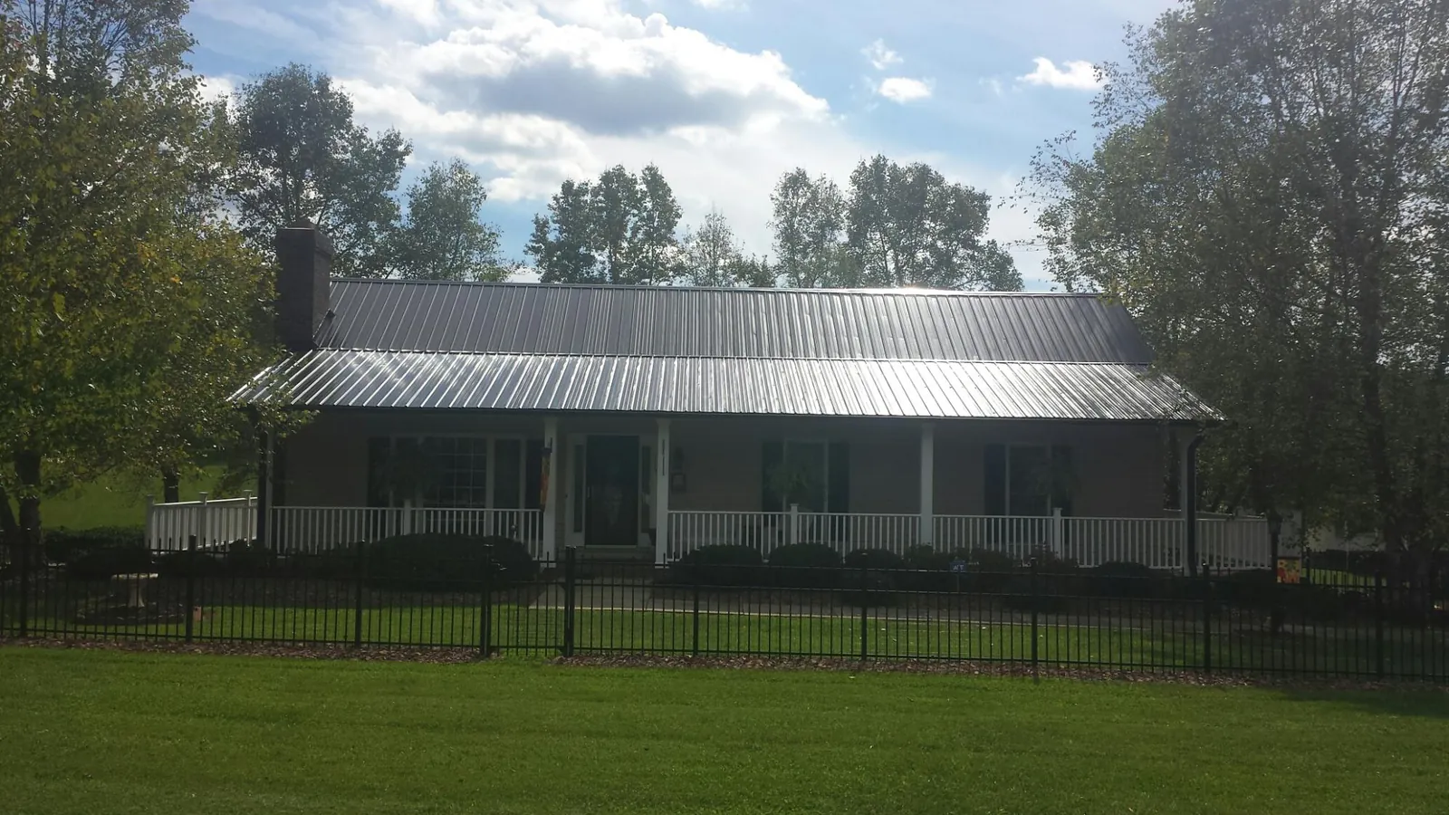 Gray metal roof on a brick ranch with a full width front porch — Gutter Guard Installation work by our crew in Hughson