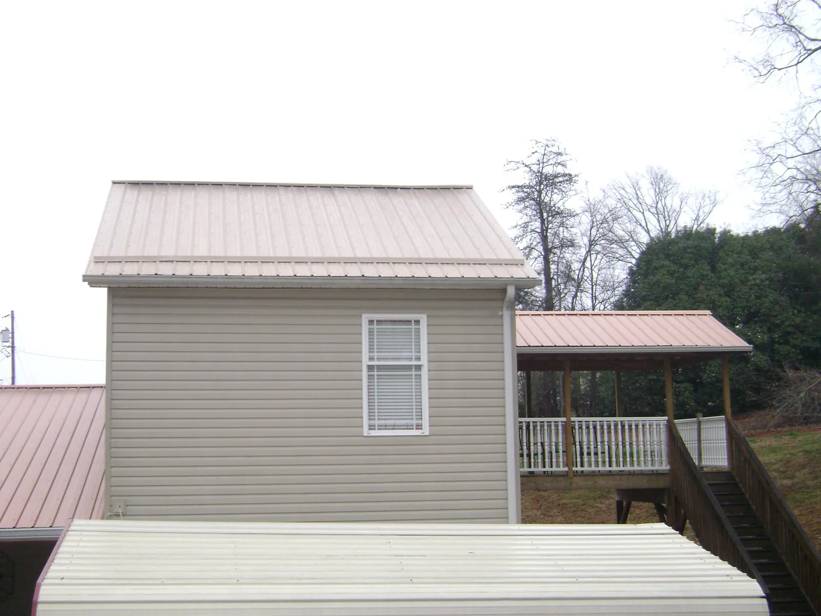 Tan metal roofs on a two story addition and attached porch, from a Roof Replacement job in Hughson