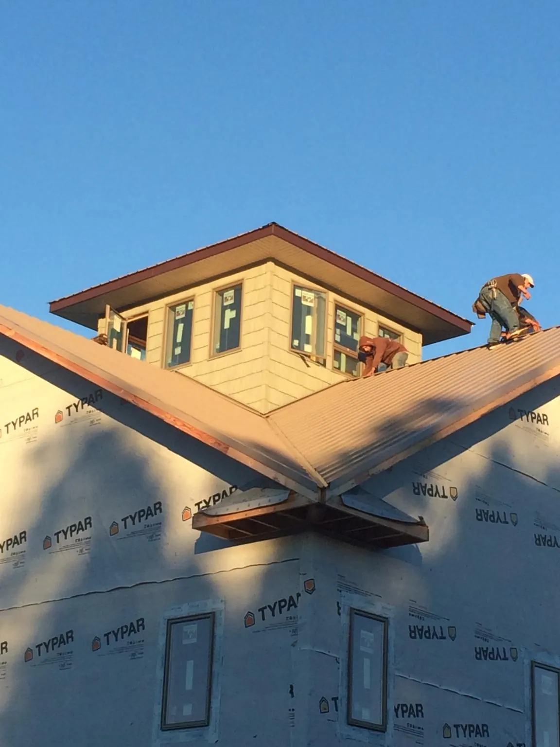 Roofers working around a rooftop cupola on a new metal roof at sunset — Roof Waterproofing in Hughson by Roofing Brothers